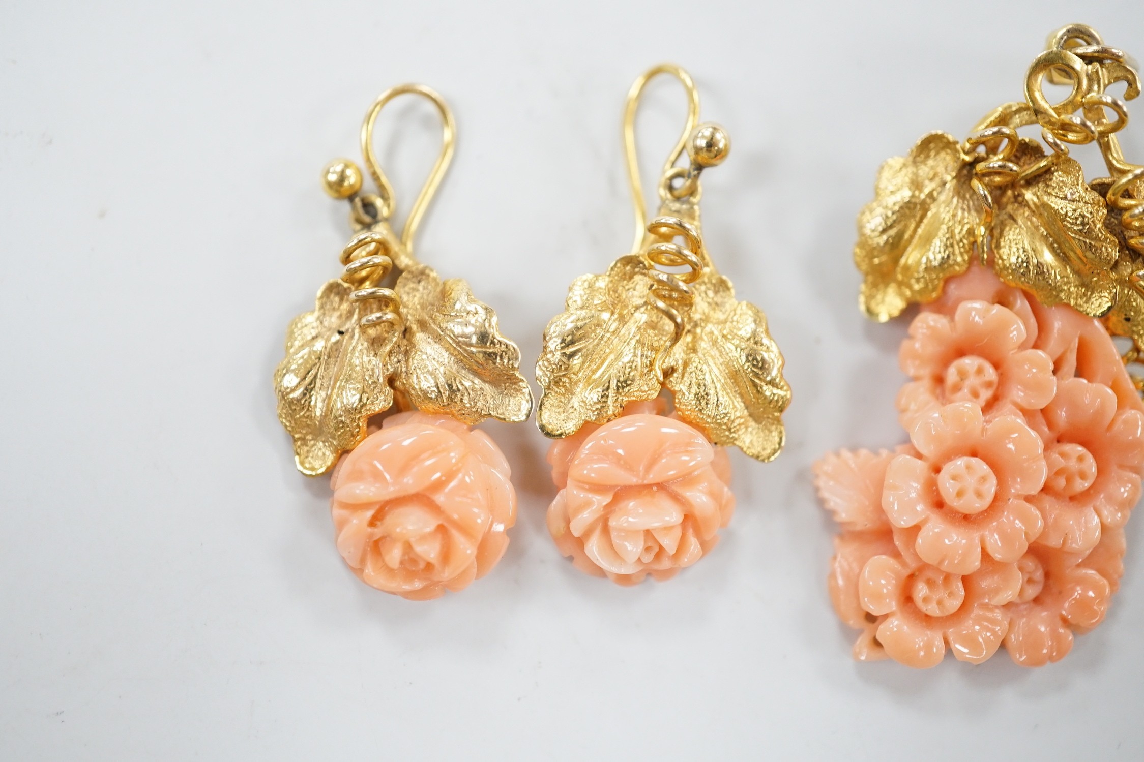 A modern suite of yellow metal and carved coral jewellery, comprising a pendant , 40mm, on chain, 45cm and a pair of matching drop earrings stamped 9ct gold, 26mm, gross 15.2 grams.